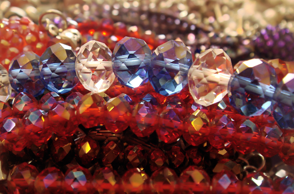 Perles en verre taillées avec facettes brillantes en nuances de bleu, de rouge et de blanc.