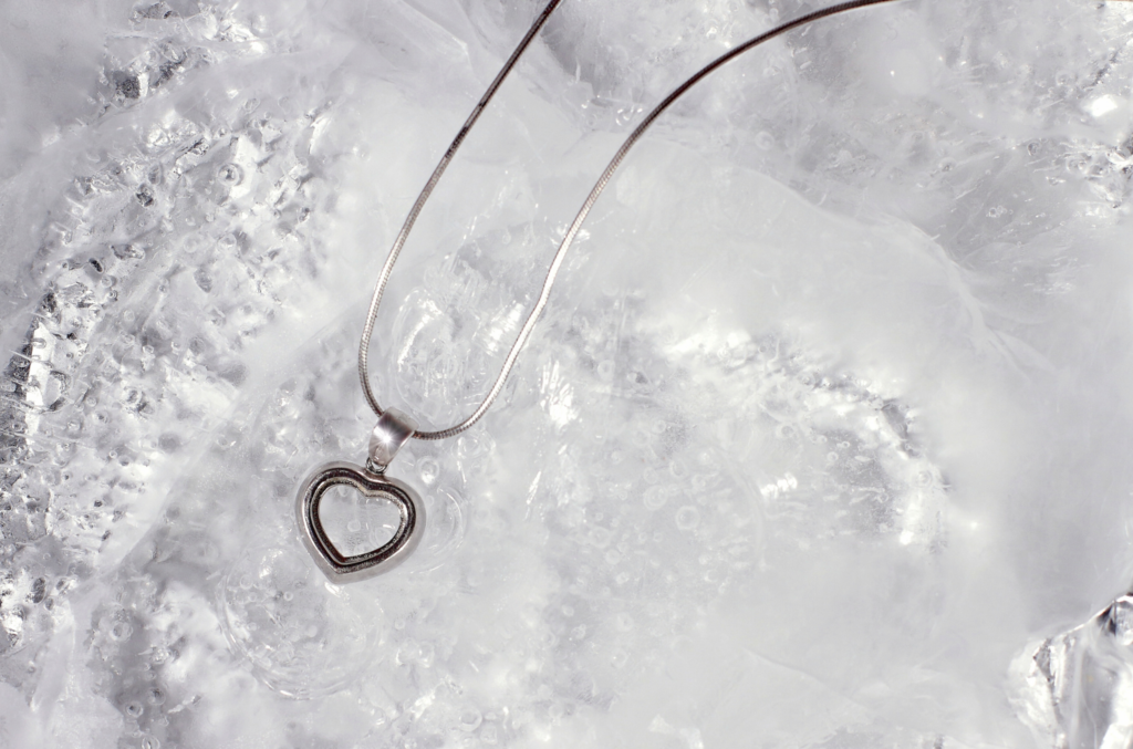 Collier en argent avec pendentif cœur posé sur de la glace.